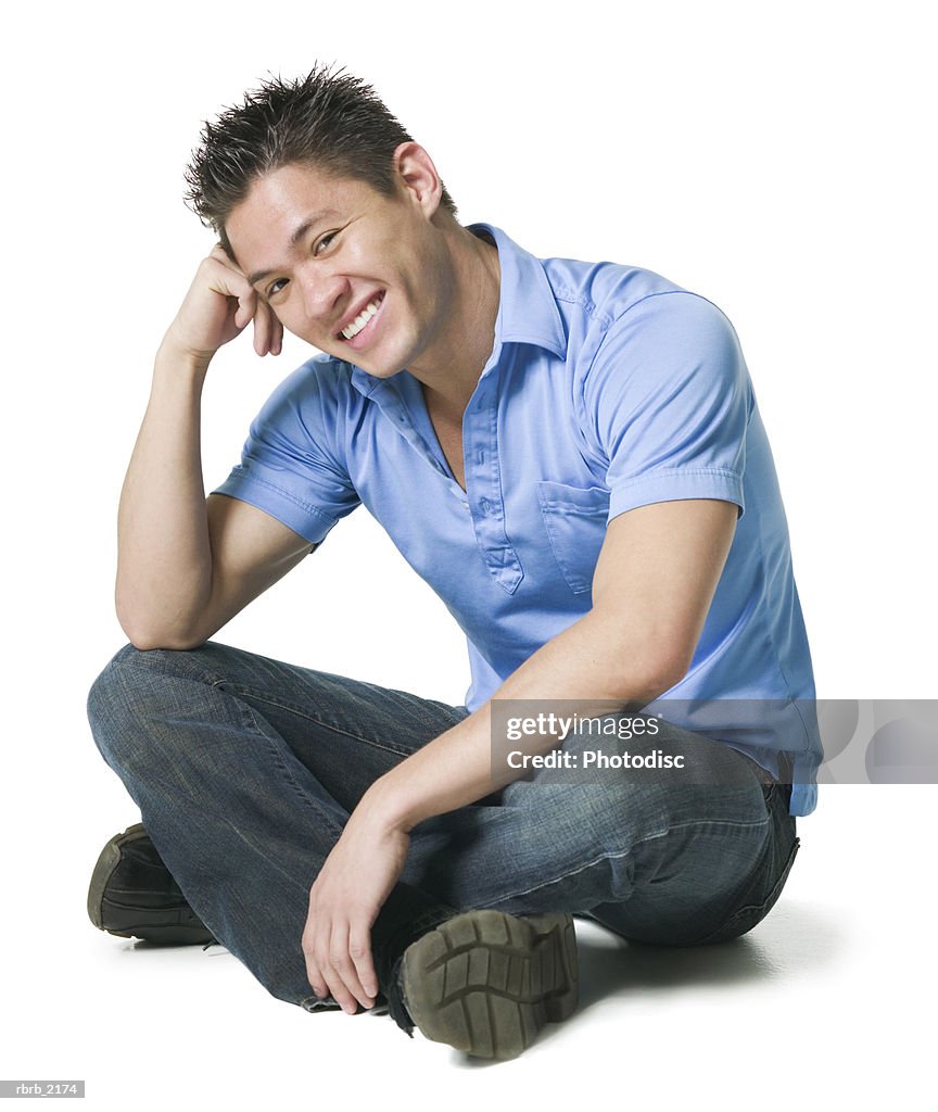 Full body shot of a young adult male in jeans and a blue shirt as he sits and smiles