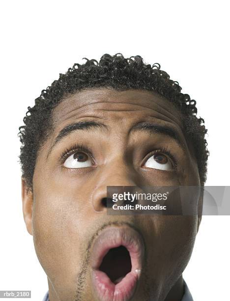 close up shot of a young adult male as he looks above his head and reacts with awe - homme en contre plongée fait le pitre photos et images de collection