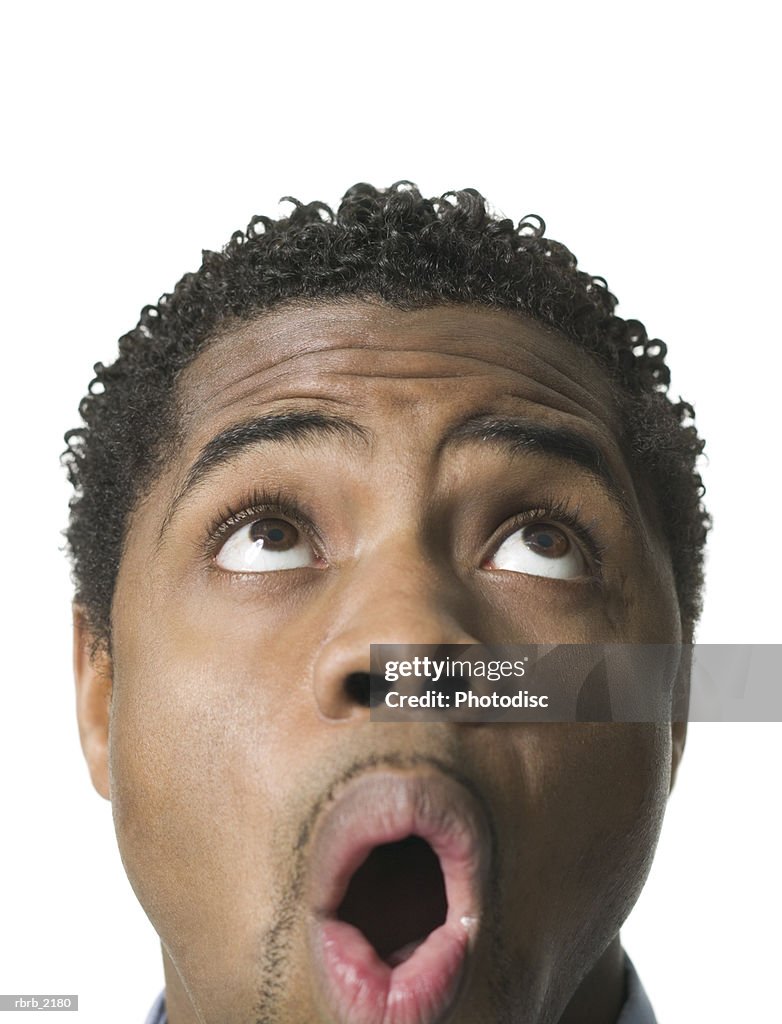 Close up shot of a young adult male as he looks above his head and reacts with awe