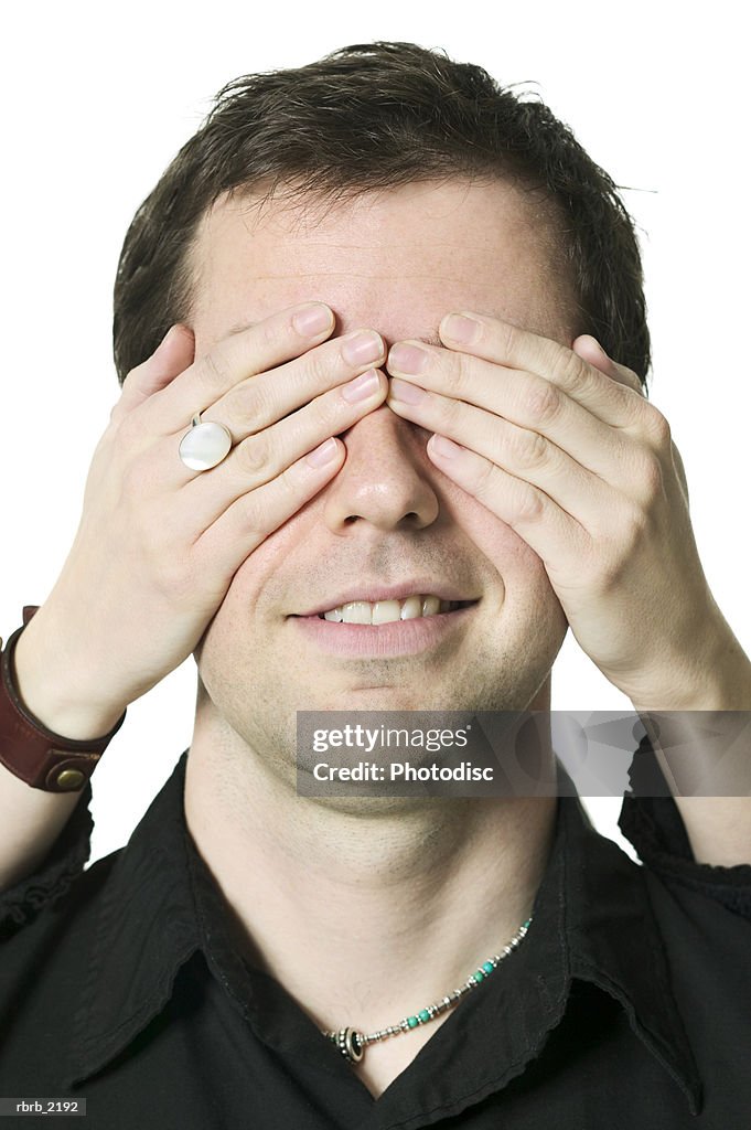 Close up shot of a young adult male as his eyes are covered for a surprise from his girlfriend