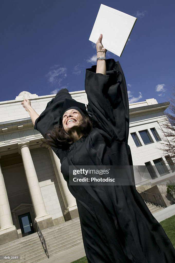 Medium shot of a young adult female in her cap and gown as she celebrates her graduation
