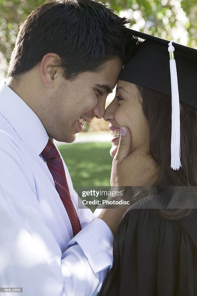 Medium shot of a young adult female college graduate as she embraces her boyfriend