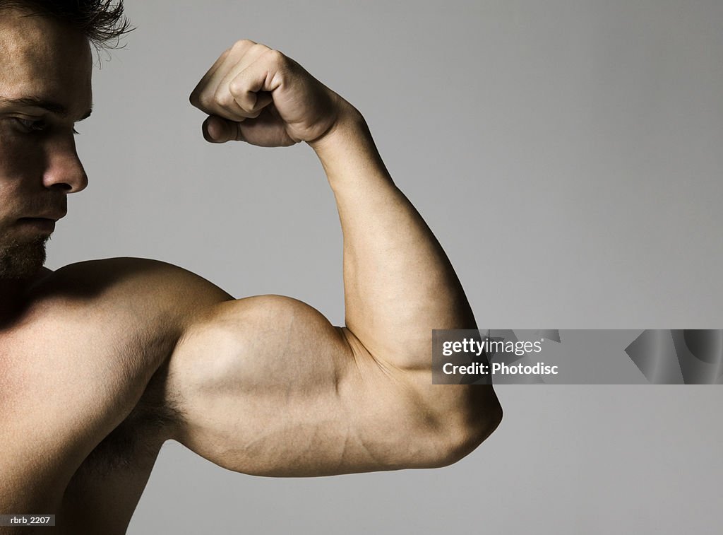 Medium shot of a muscular male as he flexes his bicep