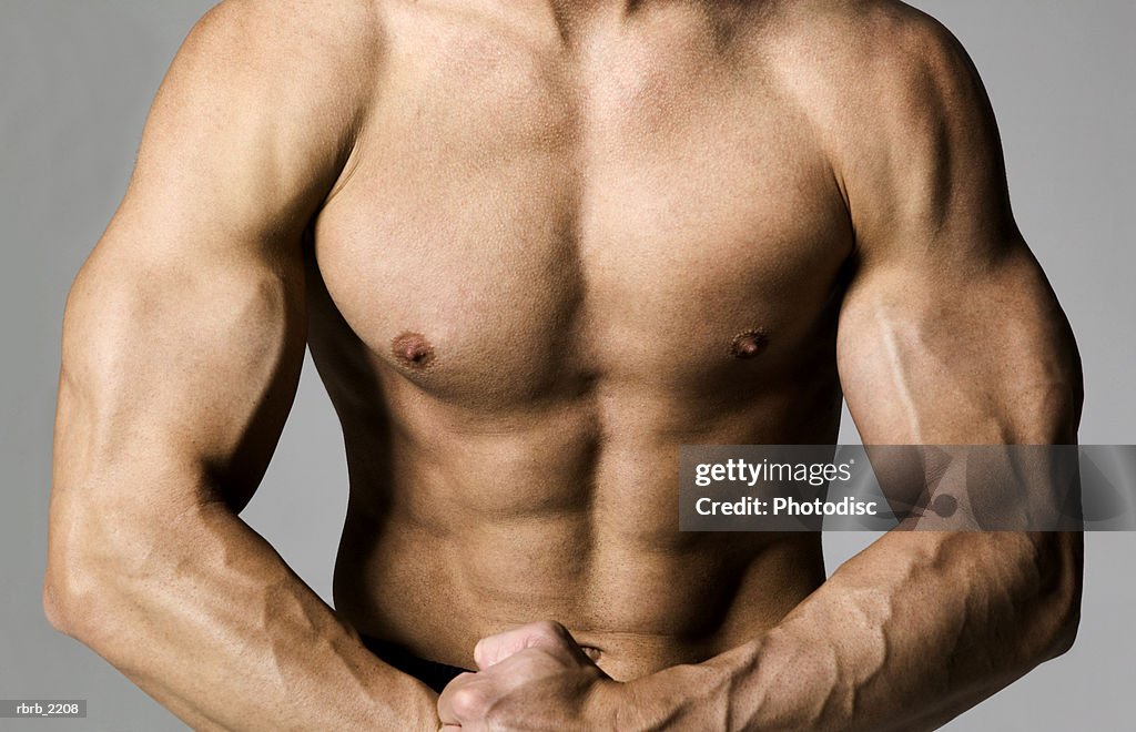 Medium shot of a fit male bodybuilder as he flexes his muscles