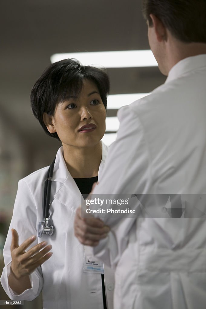 Lifestyle portrait of an adult female doctor as she chats with a colleague in the hallway