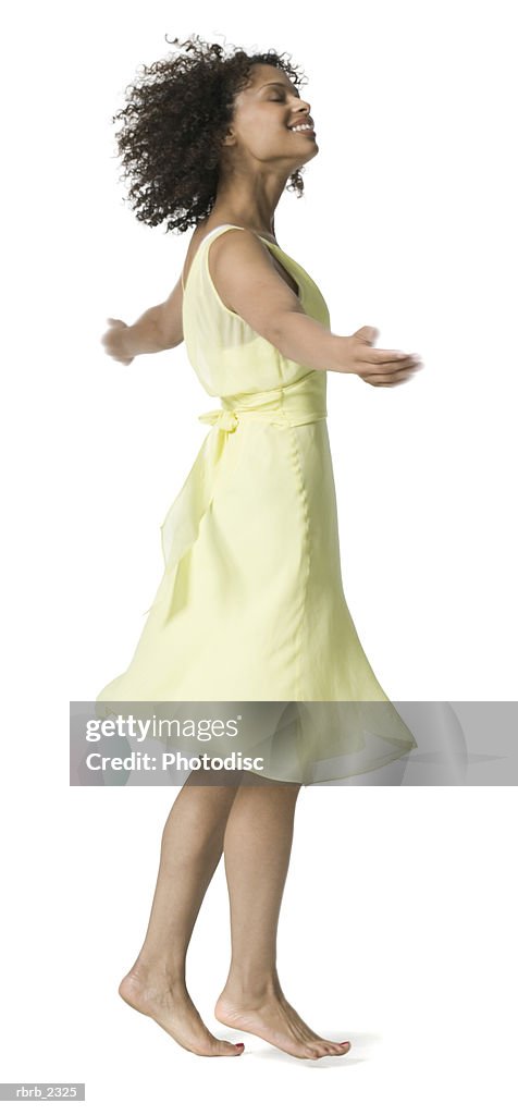 Full length shot of an attractive young adult woman in a yellow dress as she spins around