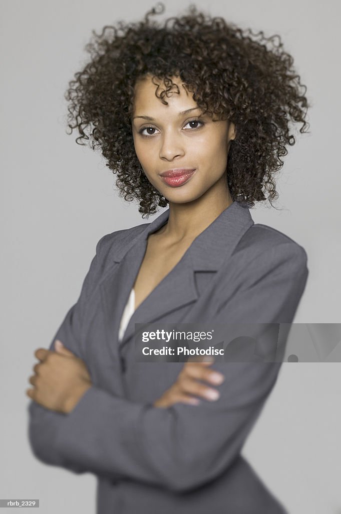 Business portrait of a young adult woman in a grey suit as she folds her arms