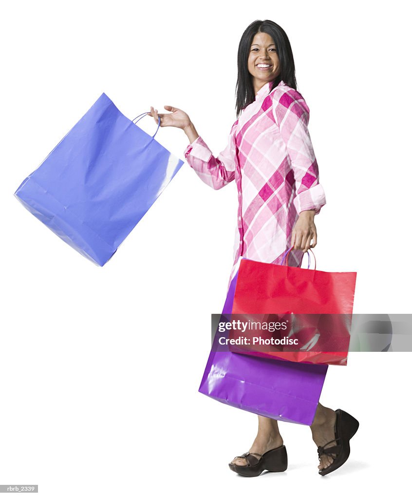 Full length shot of a young adult woman as she walks and swings her shopping bags