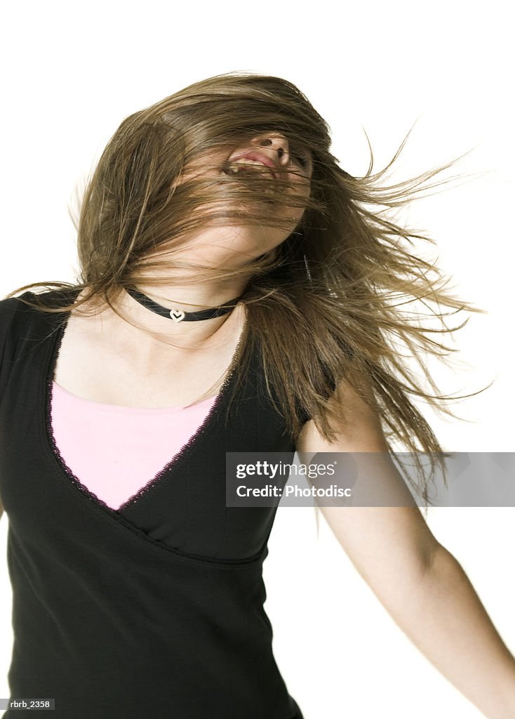 Youth portrait of a teenage female in a black shirt as she tosses her hair around