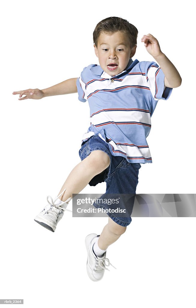 Full length shot of a male child in a blue stripped shirt as he runs and jumps through the air