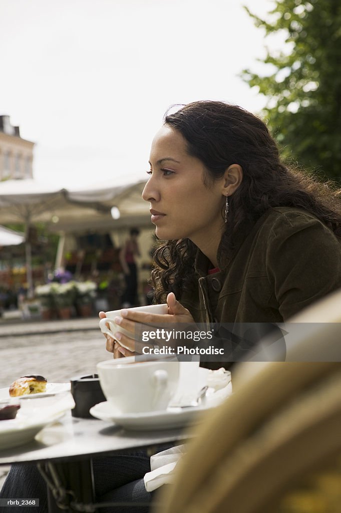 Lifestyle portrait of a young adult woman as she sits at an outdoor cafe