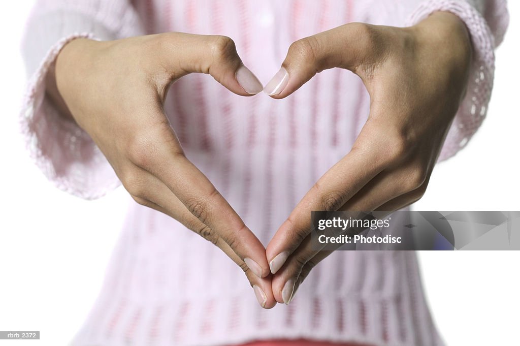 Close up shot as a young woman makes a heart shape with her hands