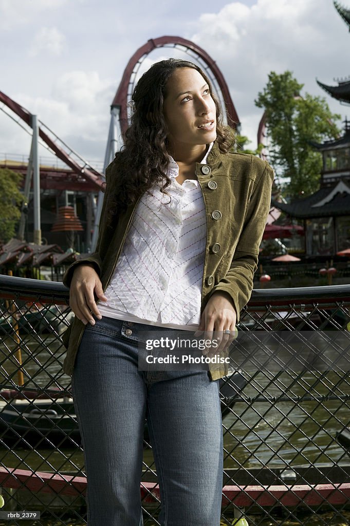 Lifestyle shot of a young adult woman as she poses under a roller coaster