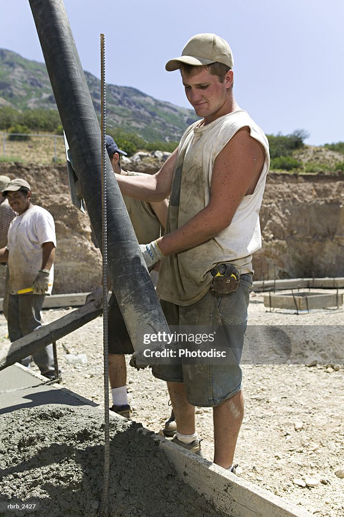 Lifestyle shot of an adult male construction worker in work clothes as he pours cement