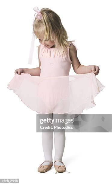 full length shot of a young female child in a pink ballet outfit as she plays with her tutu - dancing studio shot stock pictures, royalty-free photos & images