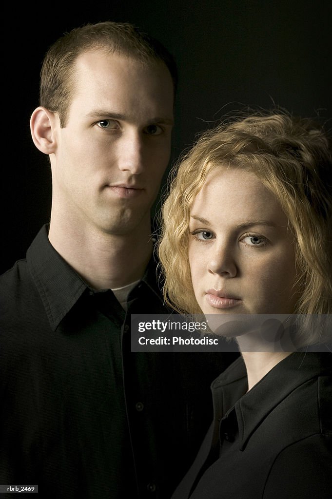 Relationship portrait of a young couple dressed in black as they look around