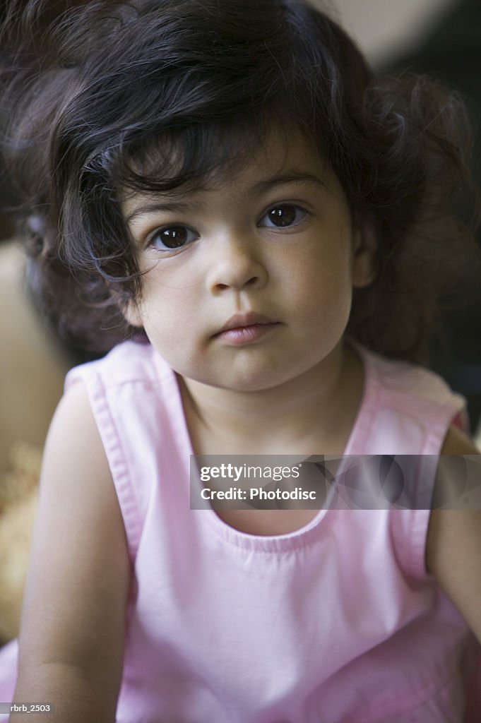 Lifestyle shot of a young female toddler in a pink dress as she looks up at the camera