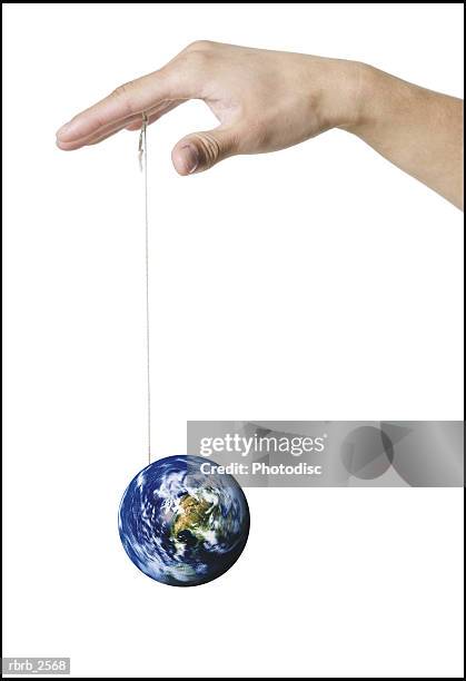 conceptual shot of a hand playing with an earth yo yo dangling on a string - world at your fingertips fotografías e imágenes de stock