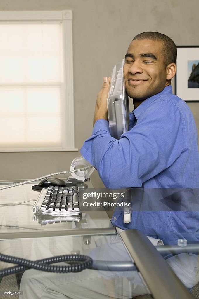 Conceptual shot of a young adult male as he lovingly hugs his computer screen