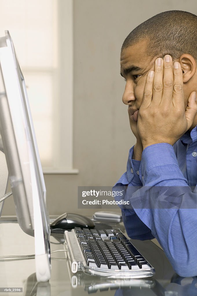 Conceptual shot of a young adult man as he waits patiently at his computer