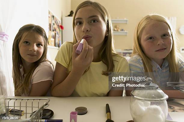 teenage lifestyle shot of three female friends as they sit at a mirror and put on make up - put together stock pictures, royalty-free photos & images