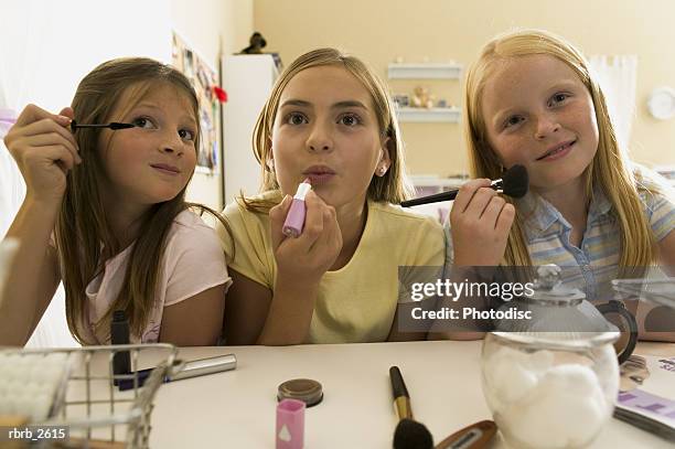 teenage lifestyle shot of three female friends as they sit at a mirror putting on make up - make up ストックフォトと画像