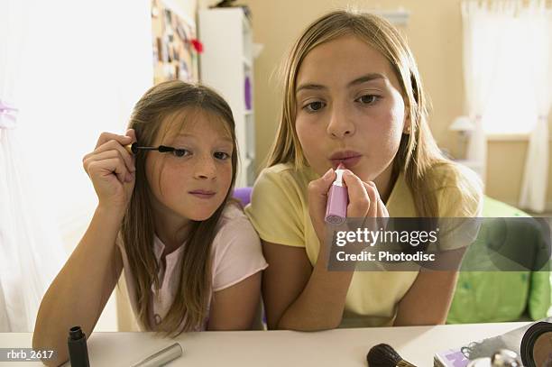 teenage lifestyle shot of two female friends as they sit at a mirror and put on make up - applying make up stock pictures, royalty-free photos & images