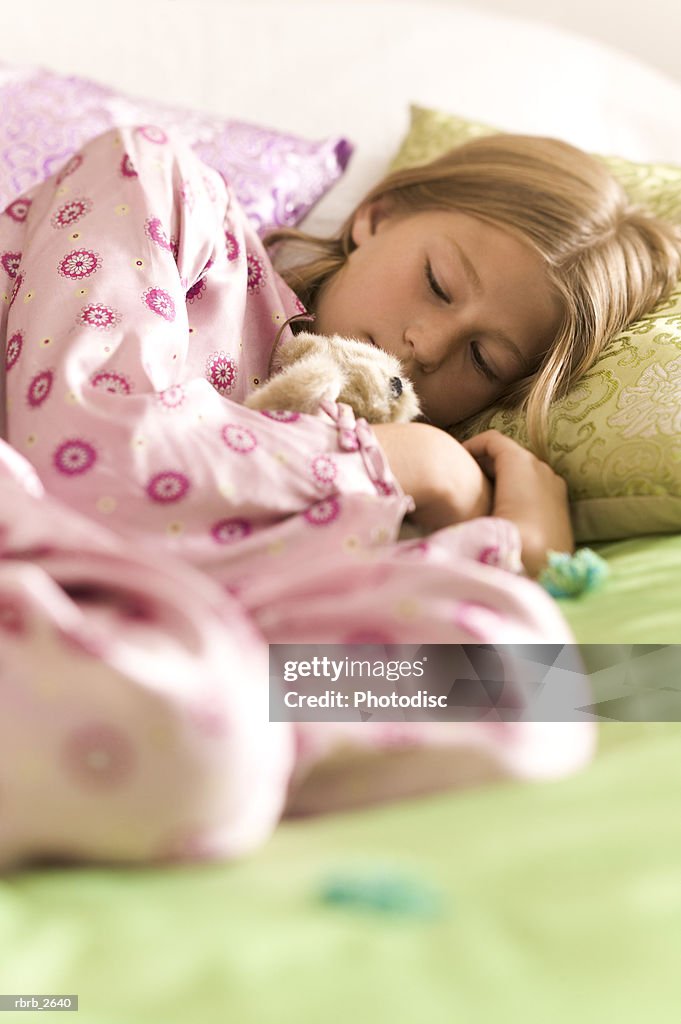 Teenage lifestyle shot of a girl in pink pajamas as she sleeps on her bed