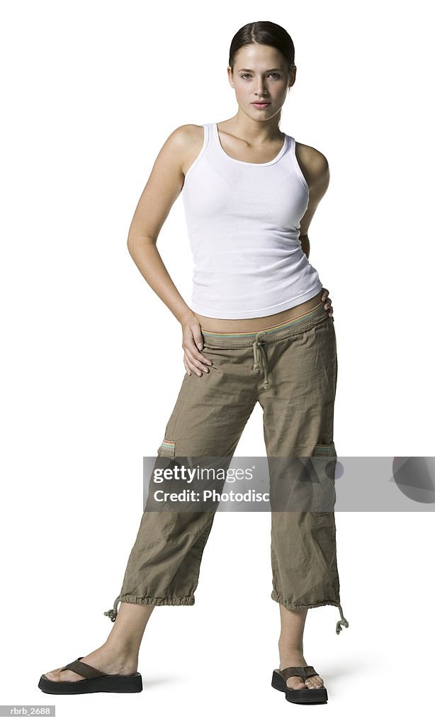 Full length shot of an attractive young adult female in a white tank top as she looks at the camera