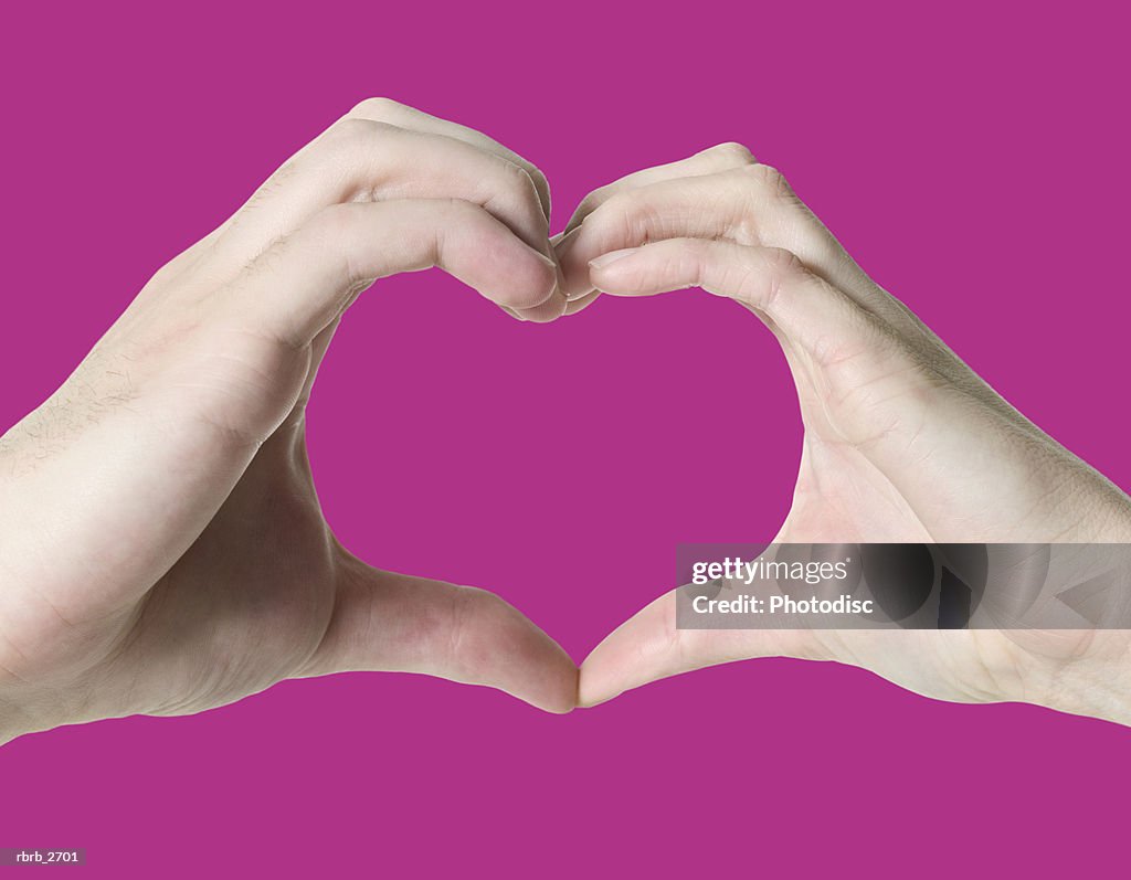 Close up on the hands of a woman as she makes the shape of a heart with her fingers