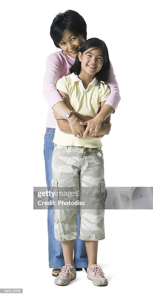 Full length shot of a mother as she smiles and hugs her teenage daughter