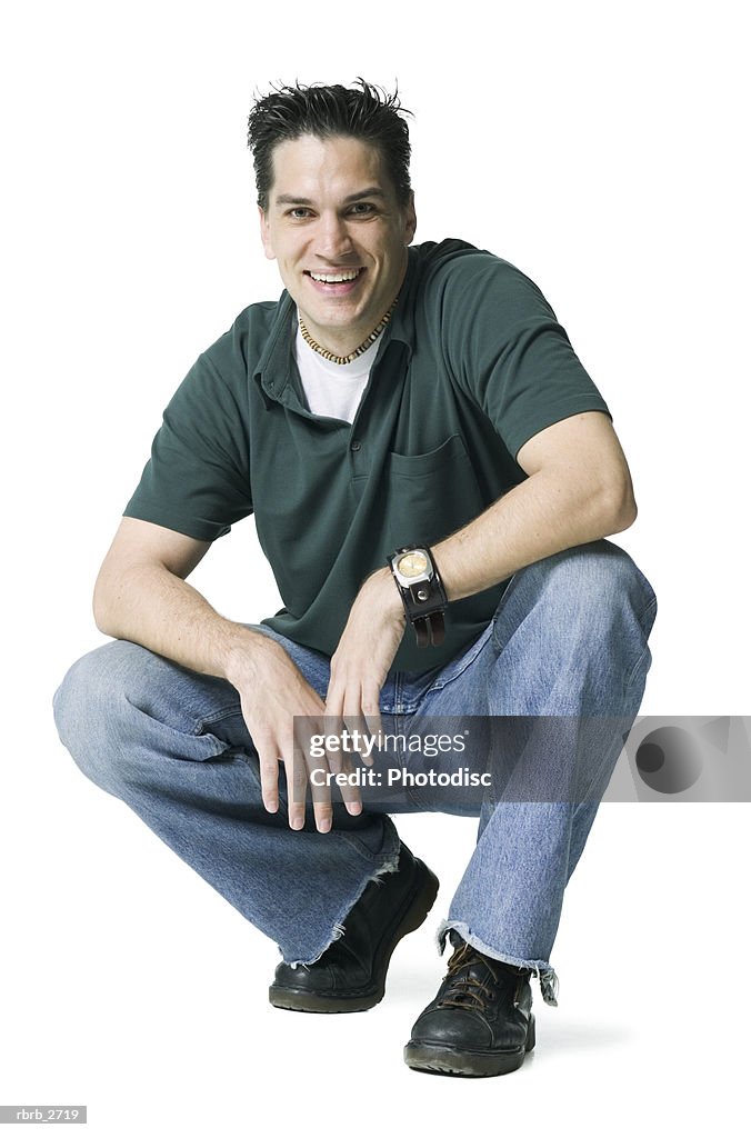 Full length shot of a young adult male in a green shirt as he crouches down and smiles