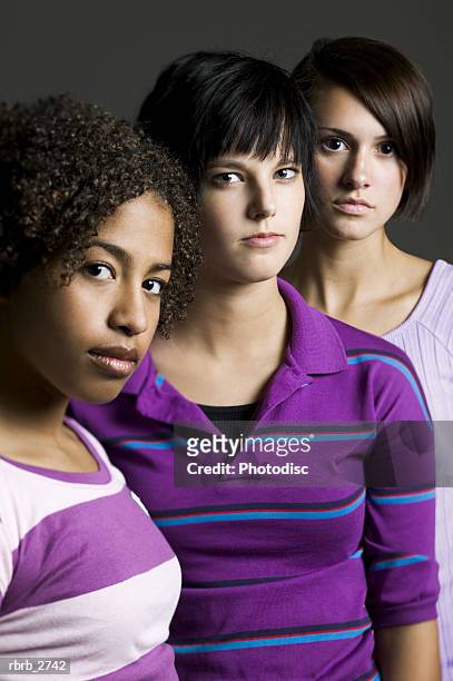 portrait of a group of three teenage female friends as they all look seriously at the camera - all stock pictures, royalty-free photos & images