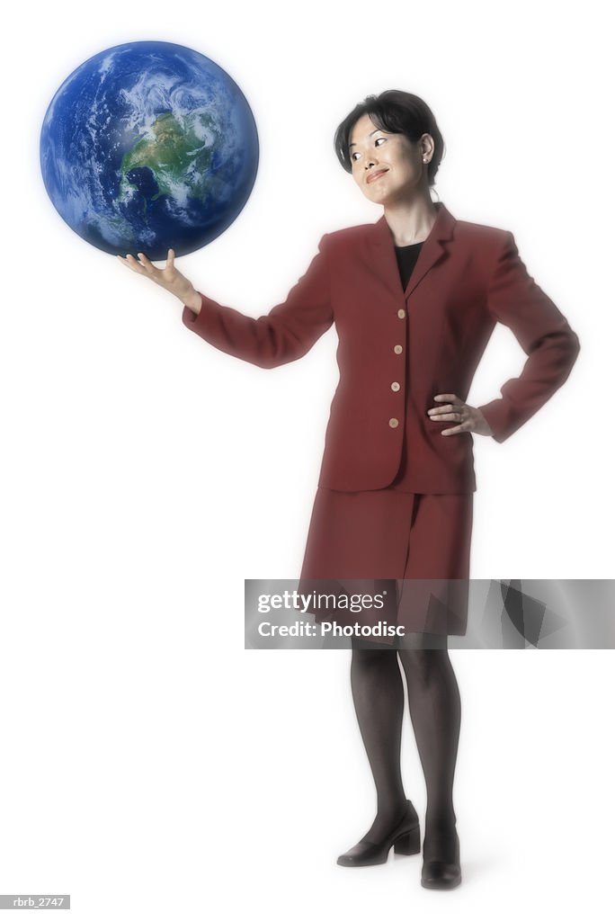 Conceptual shot of an adult business woman in a red dress as she holds up the whole world