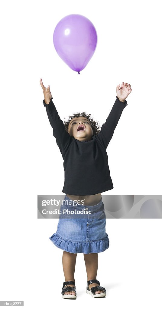 Full length shot of a female child as she looks up playing with a balloon