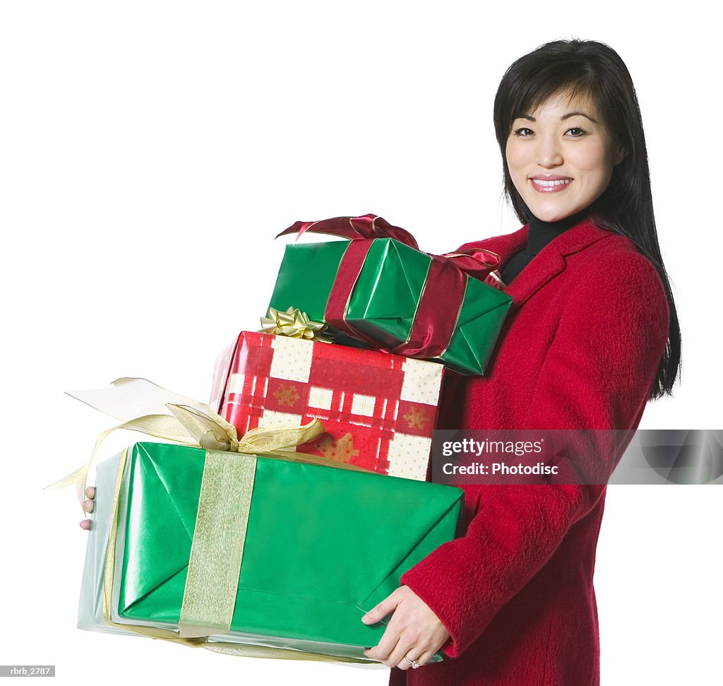 Portrait of a young adult female in a red coat as she carries some christmas presents