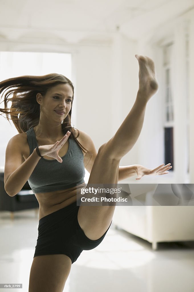 Fitness lifestyle shot of an attractive young adult female in workout clothes as she kicks up into the air