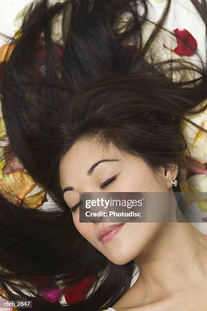 young woman lying on flower petals - rose petals on bed stock pictures, royalty-free photos & images