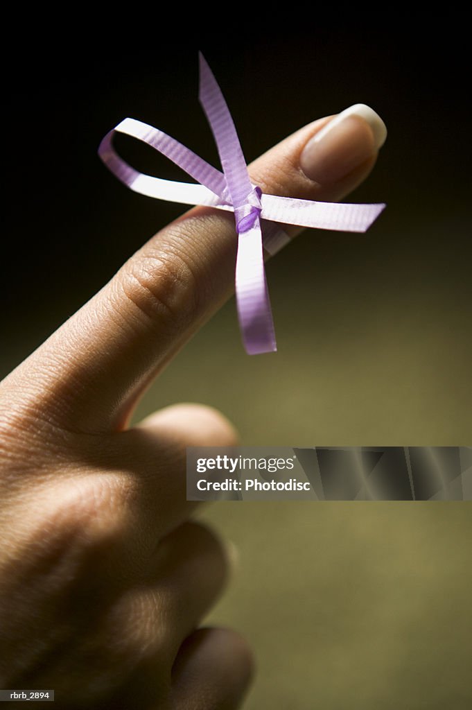 Close-up of a human finger with a ribbon tied in a bow