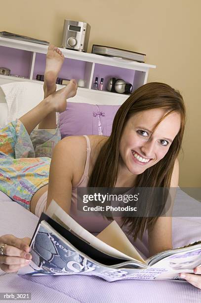 portrait of a teenage girl lying on a bed holding a magazine - teen soles stock pictures, royalty-free photos & images