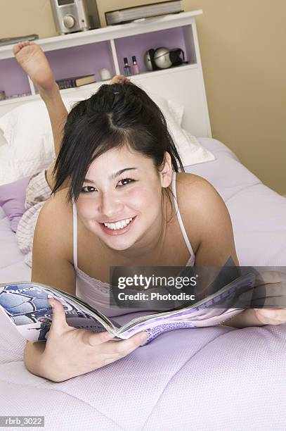 portrait of a teenage girl lying on a bed holding a magazine - teen soles stock pictures, royalty-free photos & images