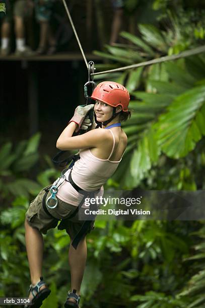 rear view of a teenage girl suspended on a rope in the forest - baumkrone stock-fotos und bilder