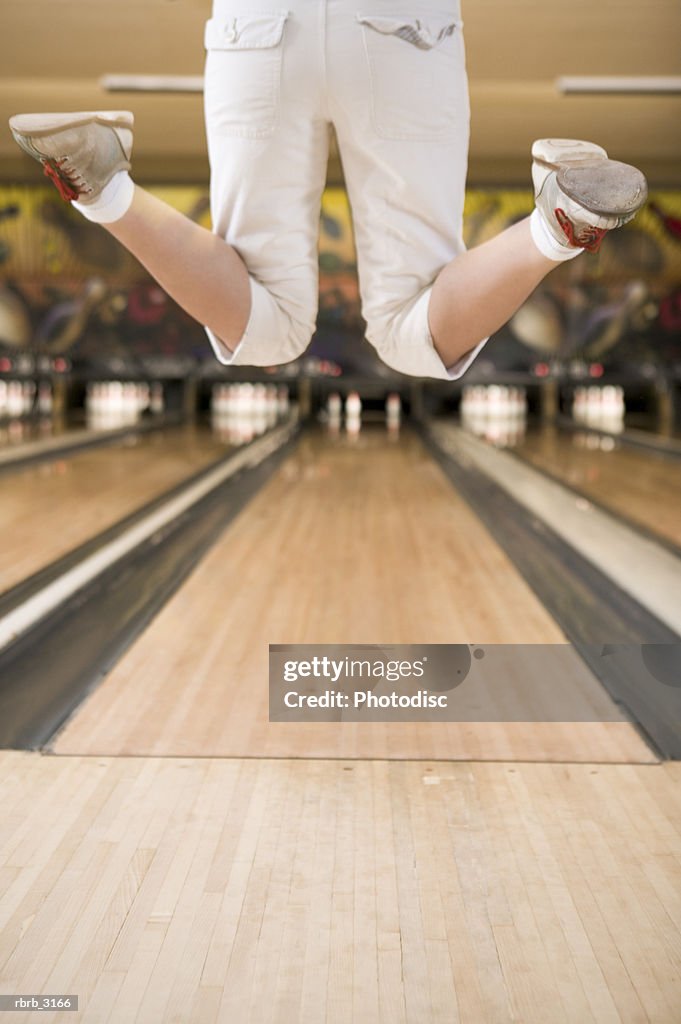 Rear view of a person's feet jumping at a bowling alley