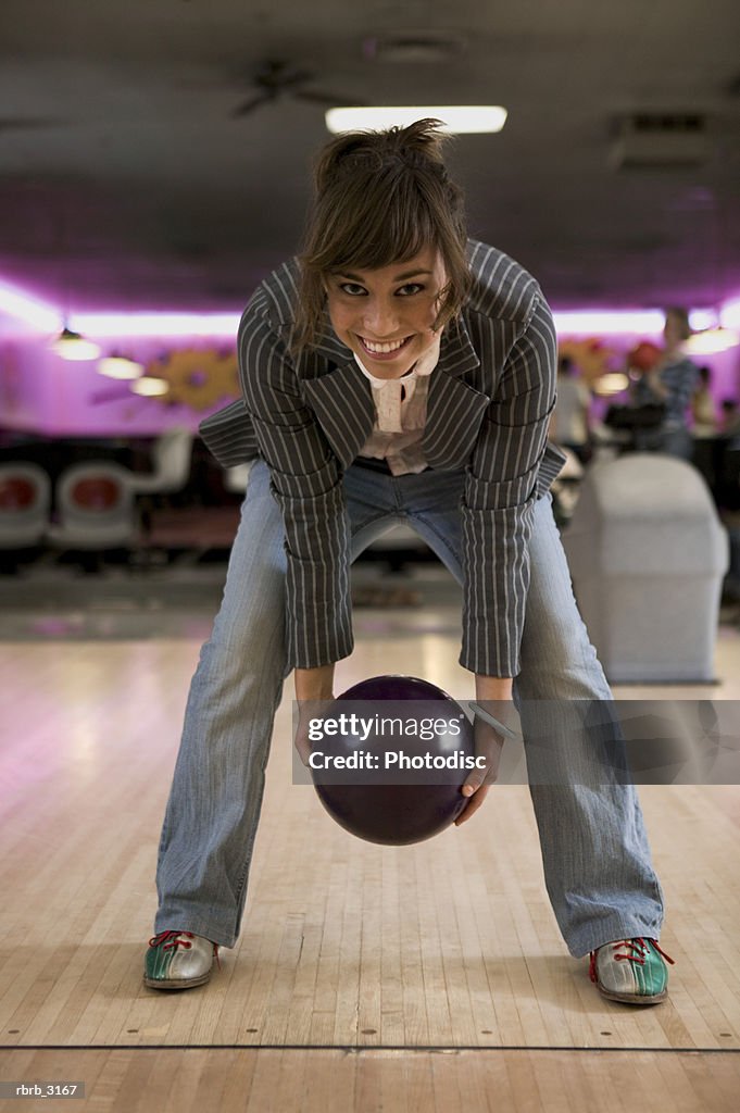 Portrait of a young woman holding a bowling ball at a bowling alley