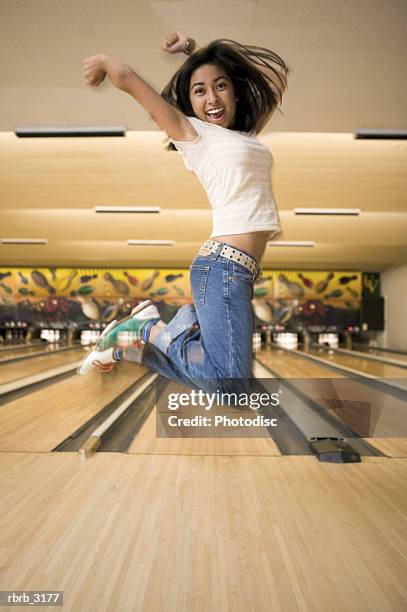 young woman jumping at a bowling alley - bowling shoe stock pictures, royalty-free photos & images