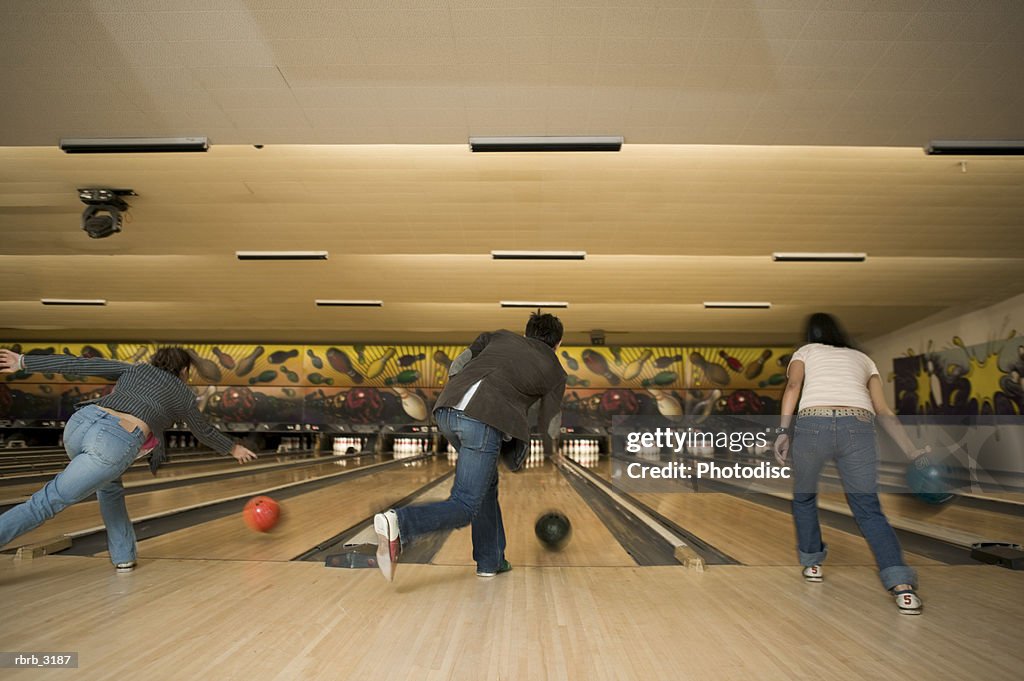 Rear view of three people bowling at a bowling alley