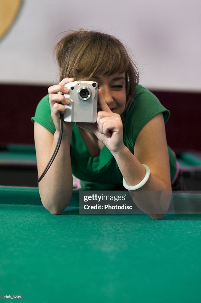 Young woman holding a digital camera over a pool table