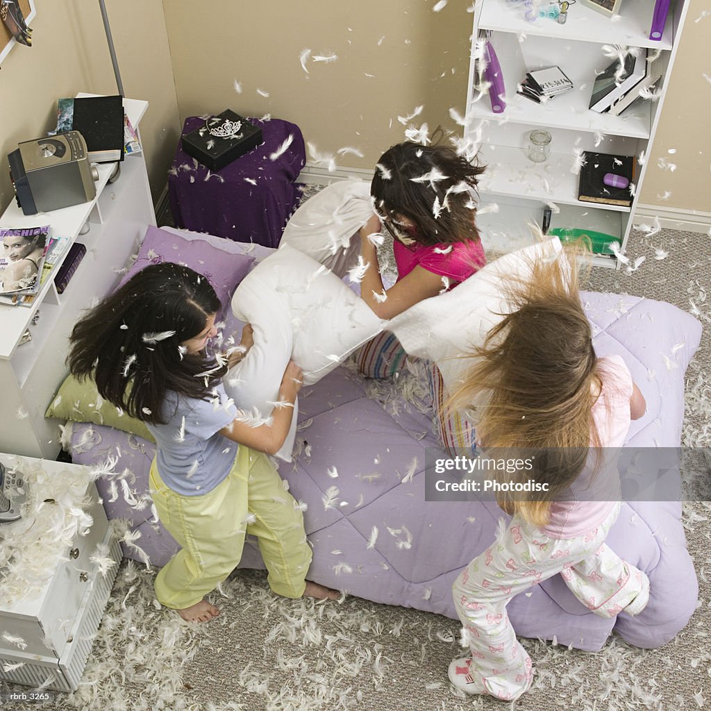 High angle view of three teenage girls having a pillow fight