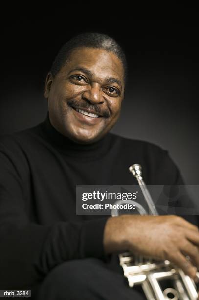 portrait of a man holding a trumpet - bläser stock-fotos und bilder