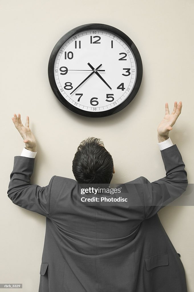 Rear view of a businessman looking up at a wall clock